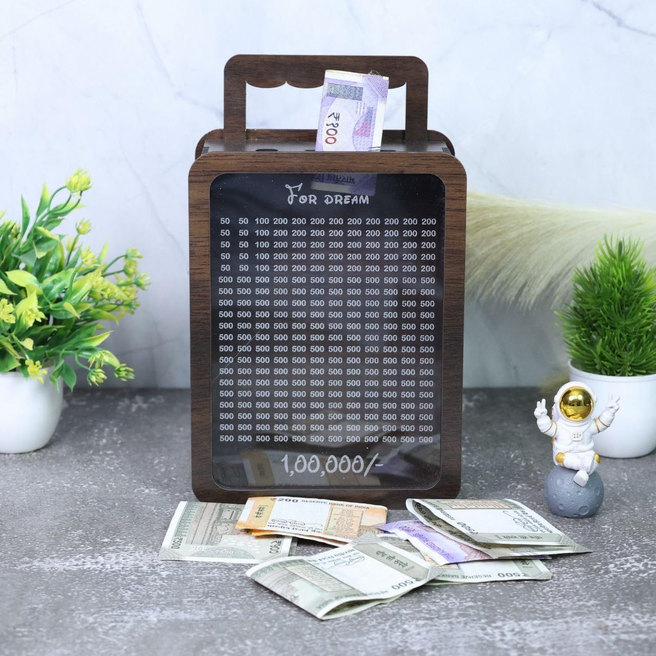 Wooden money box with digital display on a surface with scattered money and decorative items.